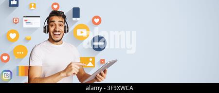 Smiling Young Middle Eastern Man Using Tablet And Headphones, Business Concept Stock Photo