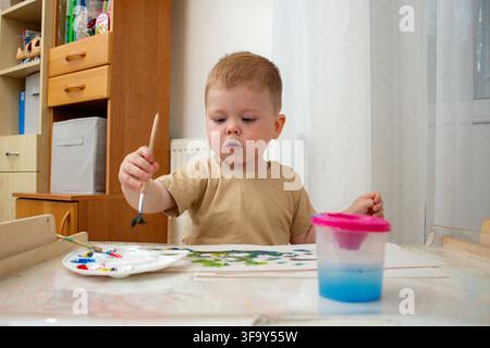 Child engaged in messy watercolor play. Art as therapy for emotional growth. Screen free childhood creativity, kid development without digital and mod Stock Photo