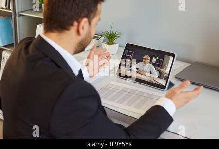Businessman holding tablet with online video call during remote office meeting Stock Photo