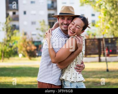 Affectionate couple holding each other and smiling as they enjoy quality time together outdoors. Stock Photo
