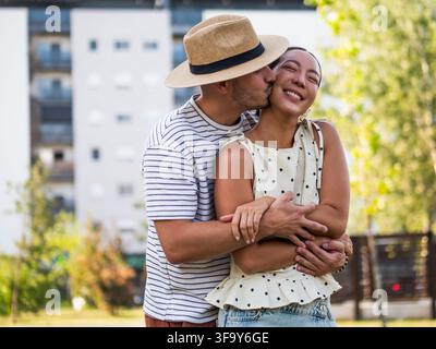 Loving couple enjoying a tender and playful moment together against a bright outdoor background. Stock Photo