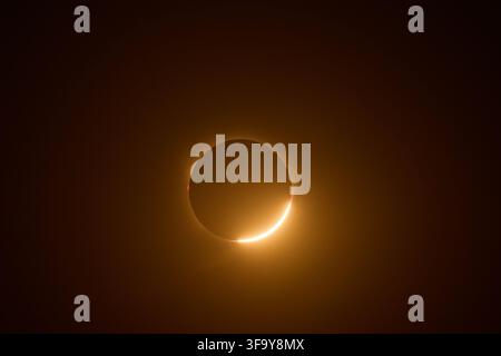 Moon obscuring the sun during a total solar eclipse, creating a stunning diamond ring effect and solar corona visible in the dark sky, highlighting an Stock Photo