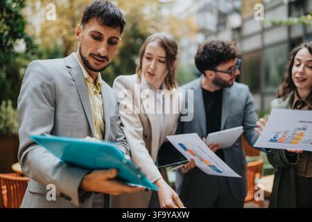Business team discussing reports during an outdoor meeting on an office terrace Stock Photo