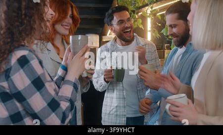 Cheerful diversity people five friends business team men women dancing drinking coffee in office cafe laughing enjoying dance listening music together Stock Photo