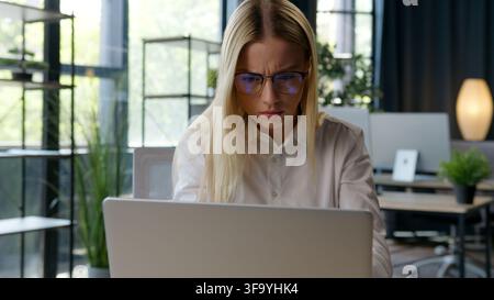Caucasian business woman feeling confusion with bad broken glasses looking in laptop take of eyeglasses trying focusing on computer work girl female Stock Photo