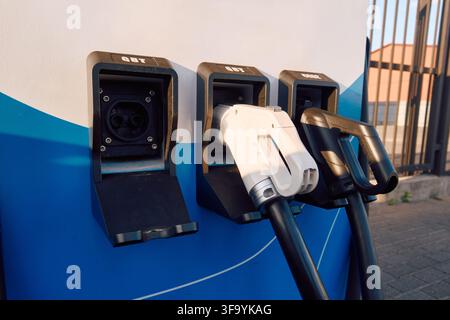 electric vehicle charging station in outdoor parking area with modern and functional design, close-up view of plastic and metal connectors, blue and Stock Photo