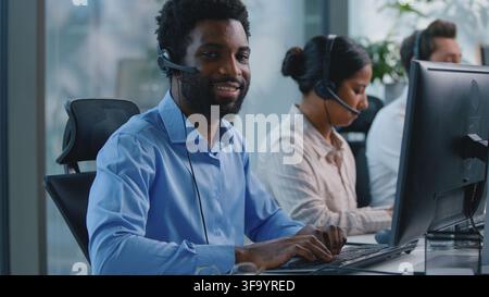 African American business man working in call center typing computer chat keyboard smile businessman looking at camera smiling work online in Stock Photo