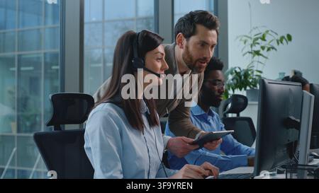 Three multiethnic operators working in call center ceo checking satisfied support woman talking with clients celebrating business success group Stock Photo