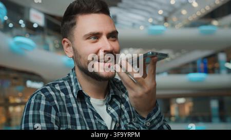 Caucasian happy smiling male man recording voice mail with mobile phone in shopping mall carefree guy record audio message with easy smartphone Stock Photo