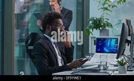 Busy multiethnic coworkers African American Caucasian men talking mobile phone cellphone multitask professional employees businessmen males business Stock Photo