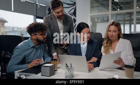 Four diversity business people with documents conference with laptop talking multiethnic cooperation in global multinational partnership company Stock Photo