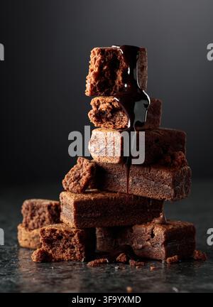 Brownie pieces on a black background. Melted chocolate drips down the brownie. Stock Photo