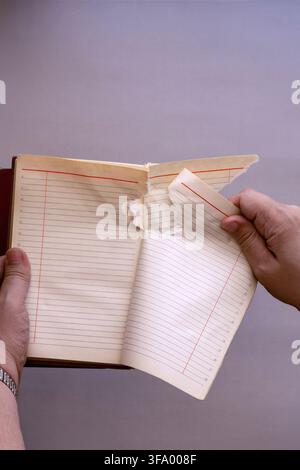 A conceptual close-up of two hands holding an open vintage ruled notebook. Stock Photo