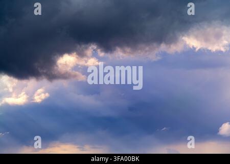 Pre-storm sky with massive dark gray clouds looming over gaps of blue sky. Stock Photo