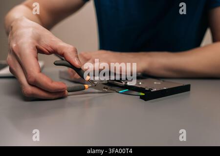 Repairing external optical disc drive using specialized electronic tools, person fixing hardware component, maintenance for portable computer Stock Photo
