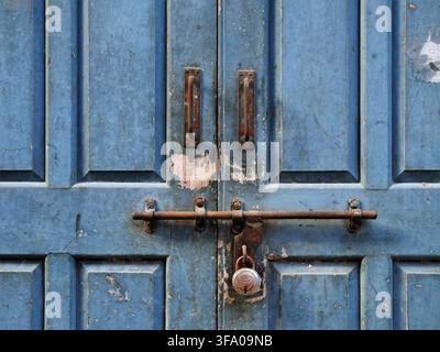 Traditional metal door latch and lock on a weathered blue wooden door Stock Photo