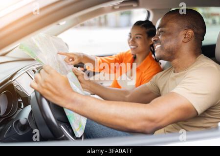 Young Black couple inside car using paper map to plan their route Stock Photo