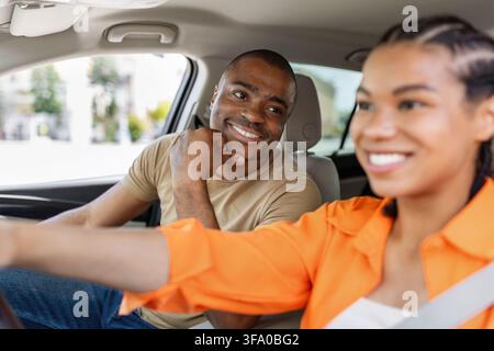 Black man smiling affectionately at his partner while they sit inside car Stock Photo