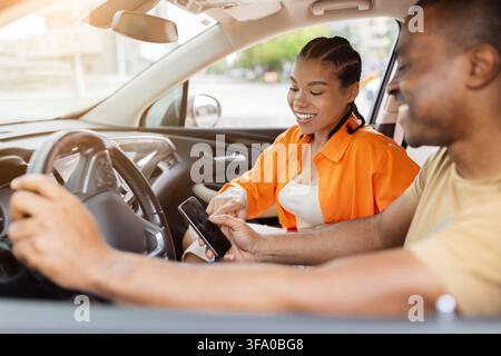 Young Black couple using smartphone together inside car Stock Photo