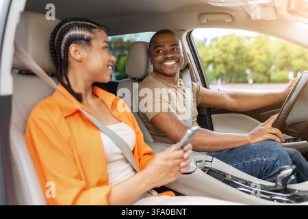 Young Black couple smiling at each other inside modern car Stock Photo