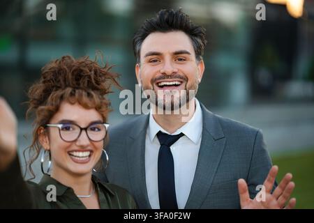 Business colleagues smiling and waving at camera Stock Photo