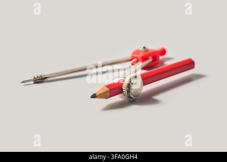 red geometry compass with pencil isolated gray background, metal and plastic drafting tool with sharp point in soft focus, close-up side view Stock Photo