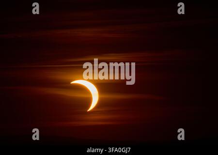 Solar eclipse over the landscape, showing dark lunar silhouette gliding across the solar disk Stock Photo