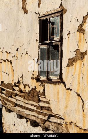 View of a weathered, cracked mud-plaster wall with exposed wooden laths and a rustic window frame in the historic village of Gostusa, Stara planina, P Stock Photo
