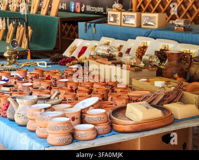 Traditional fair stall displays handcrafted clay pots and wooden bowls. Earth-toned ceramics and wooden crafts fill the table. Decorative items includ Stock Photo