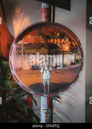 Man taking a self-portrait in a convex street mirror with flag decorations, Hanoi Stock Photo