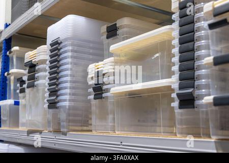 Rows of transparent storage boxes with black and yellow latches are neatly arranged on metal shelving units in a storage facility Stock Photo