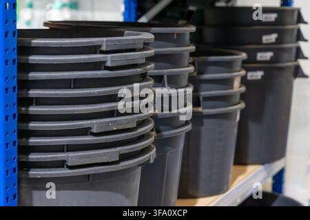 Multiple dark grey plastic containers are stacked in columns on a metal storage rack, ready for use or distribution Stock Photo