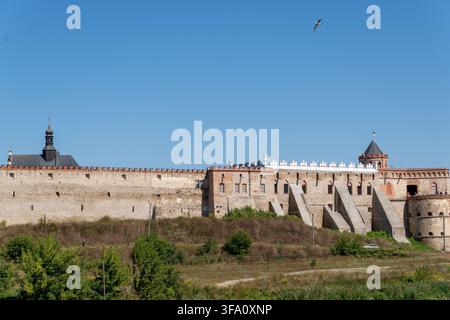 Ancient historical fortress features extensive stone walls with massive buttresses and defensive towers. Complex of medieval architecture stands on gr Stock Photo
