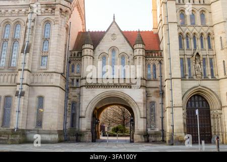 Historic Gothic archway and ornate stone facade at the University of Manchester, England, showcasing Victorian academic architecture and a quiet campu Stock Photo