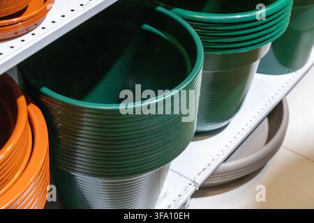Close-up view of stacked green gardening containers and orange terracotta pots displayed on a retail shelf Stock Photo