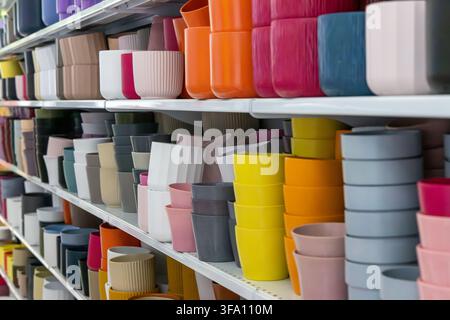 A wide variety of plastic and ceramic planters in vibrant colors and different sizes are displayed for sale in a retail environment Stock Photo