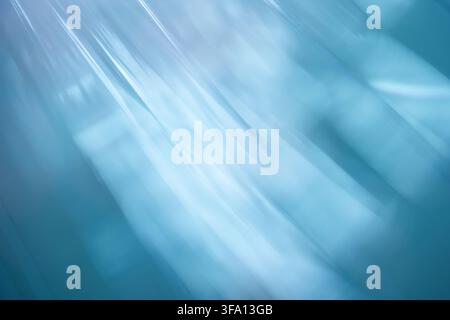 Abstract blue light rays sweep diagonally across a soft blurred background, creating an ethereal atmospheric texture with cool tones, luminous streaks Stock Photo