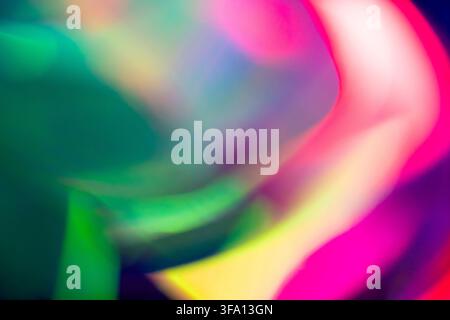 Abstract image of vibrant neon light trails in green, pink, yellow, and purple, creating a soft motion blur background with luminous curves and energe Stock Photo