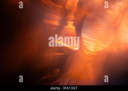 Abstract composition of vivid orange light trails and glowing circular bokeh, creating a warm, energetic background with blurred reflections, flare, a Stock Photo