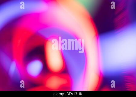 Abstract composition of neon light trails in pink, purple, red and blue, creating vibrant motion blur and glowing curved shapes for a futuristic energ Stock Photo