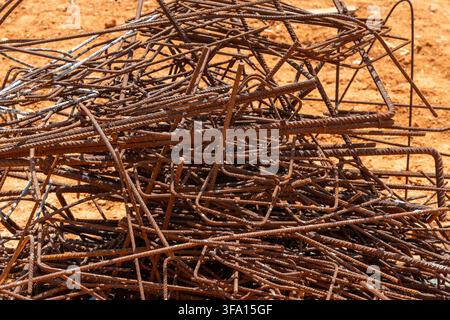 A close-up view of a tangled heap of weathered steel reinforcement bars used in concrete construction, showing signs of rust and wear Stock Photo