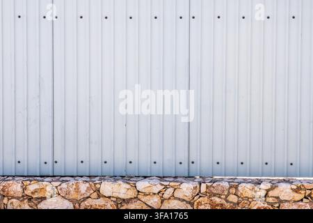 A seamless pattern of vertical corrugated metal panels meets a rustic foundation of natural stone blocks Stock Photo