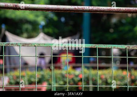Rusty green wire fence with a blurred background of a cultural activity at Ciego de Avila Zoo, Cuba - July 26, 2026 Stock Photo
