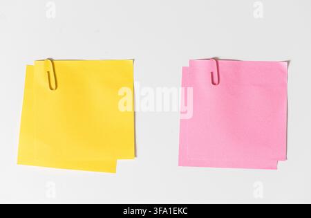 Yellow and Pink blank sticky notes with paper clips isolated on white background. Template mockup Stock Photo