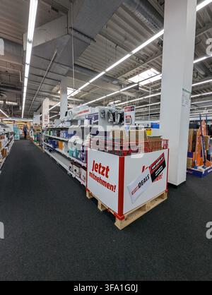 Pforzheim Germany August 3, 2026 Bright indoor view of retail electronics aisle in warehouse style store, showing rows of small devices on shelves, pa Stock Photo