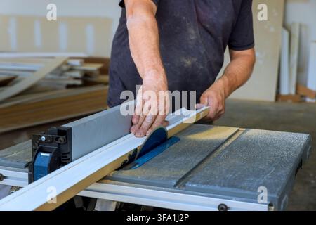 Carpenter is using table saw to cut piece of wood in workshop they focus on task at hand. Stock Photo