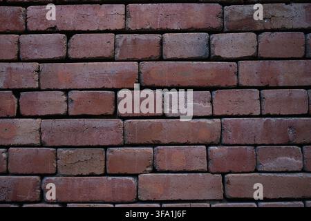 brick wall stationary in neutral setting with concrete bricks and mortar, straight-on view, red and brown tones, modern architectural background Stock Photo