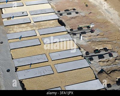 Aerial view of the BESS battery energy storage system construction site with concrete foundation slabs, electrical conduits, and sandy ground in Polan Stock Photo