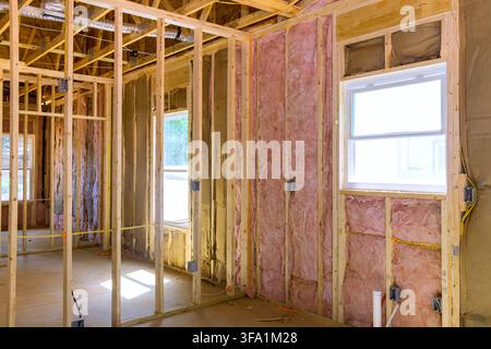 Workers are framing walls installing insulation in new building windows are visible background. Stock Photo