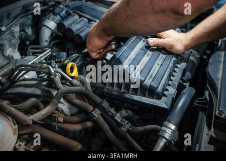 Car engine repair with mechanic hands performing diagnostics, inspection, servicing and preventive maintenance. Stock Photo
